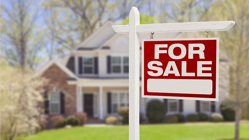 For sale sign in front of a residential real estate property before home inspection services are scheduled 